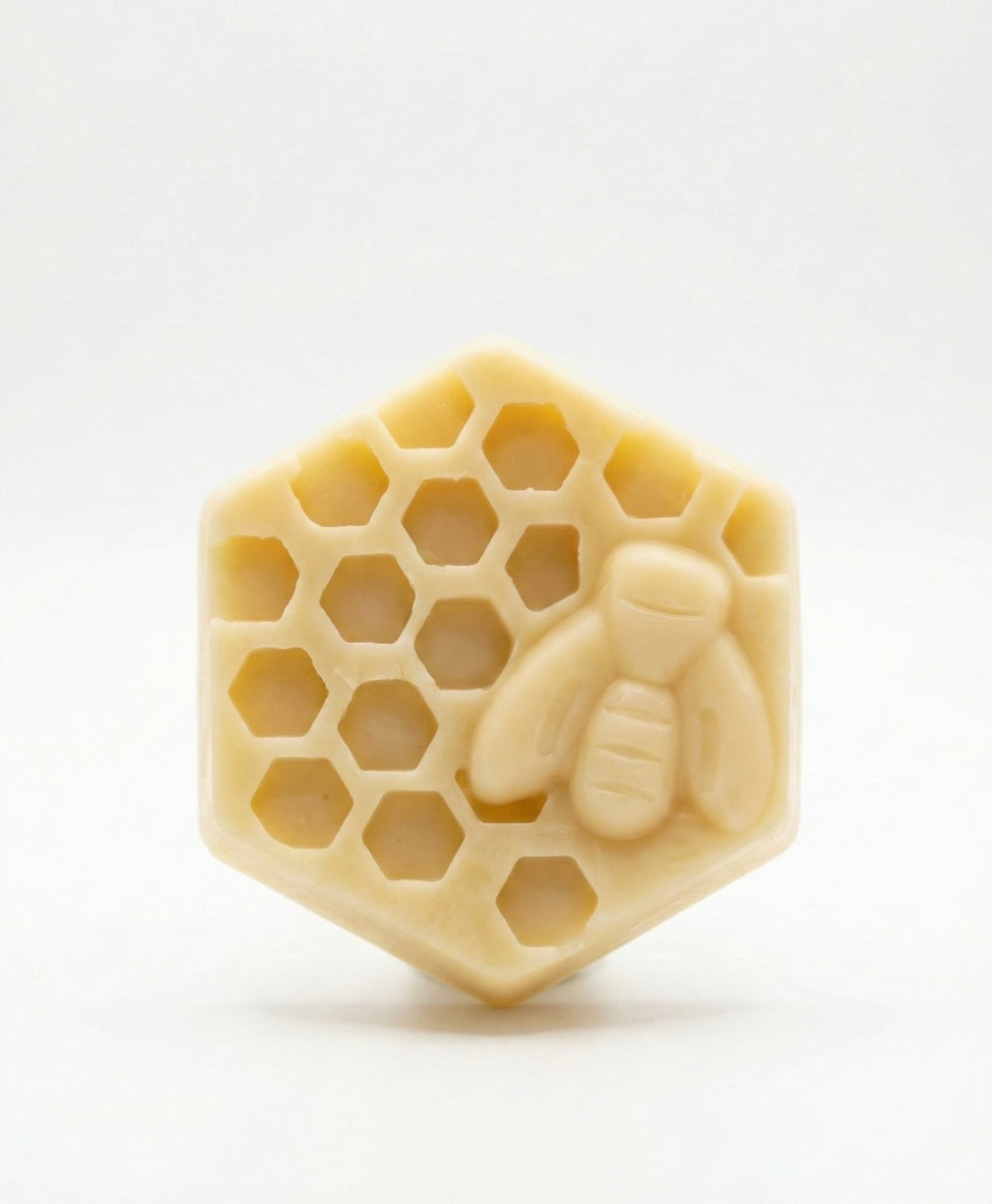 Close up of The Hive Bar by Small Town Honey Co sitting on a white marble slab. A solid hexagonal beeswax massage bar with a detailed 3D honey bee molded on top.