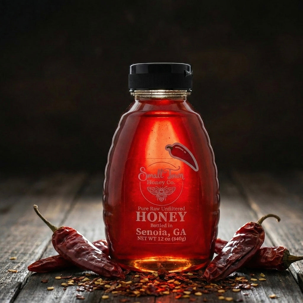 Bottle of raw hot honey surrounded by dried red chili peppers and crushed red pepper flakes to show natural ingredients.
