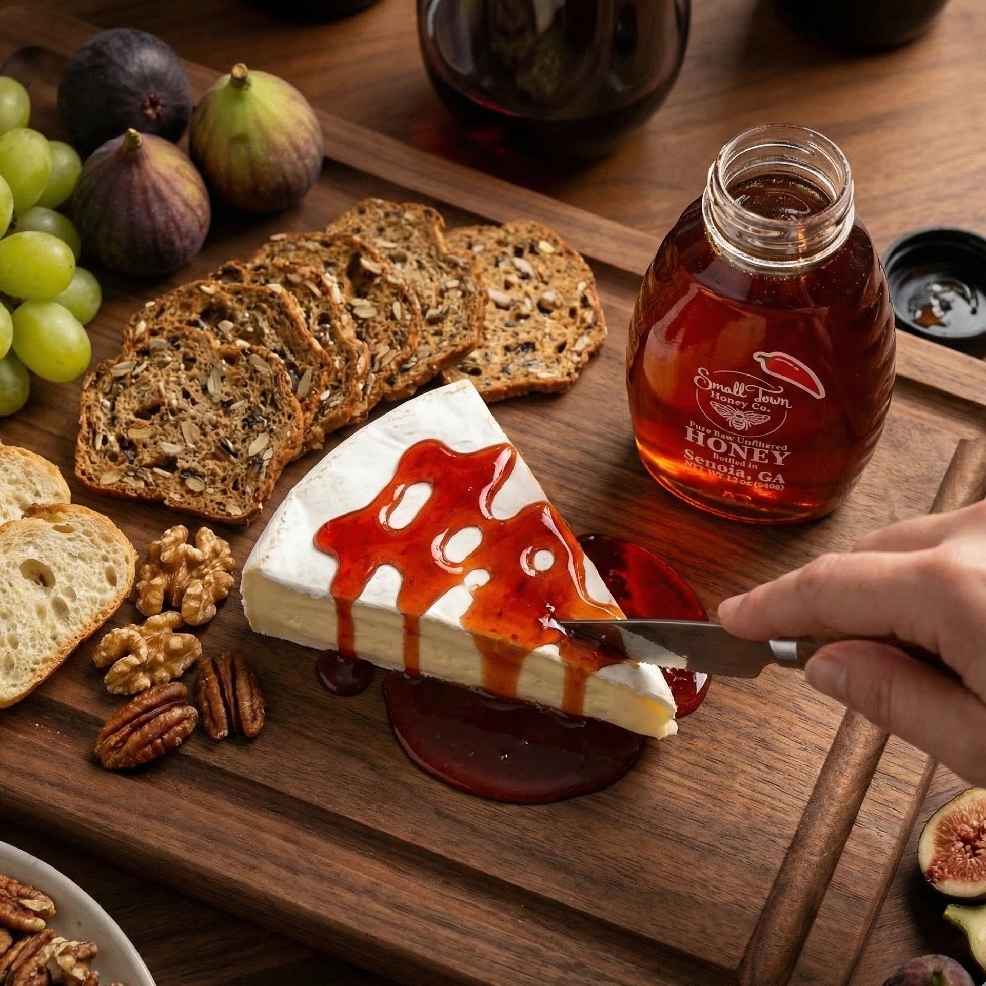 Gourmet charcuterie board featuring a wedge of brie cheese topped with spicy hot honey, figs, and artisan crackers.