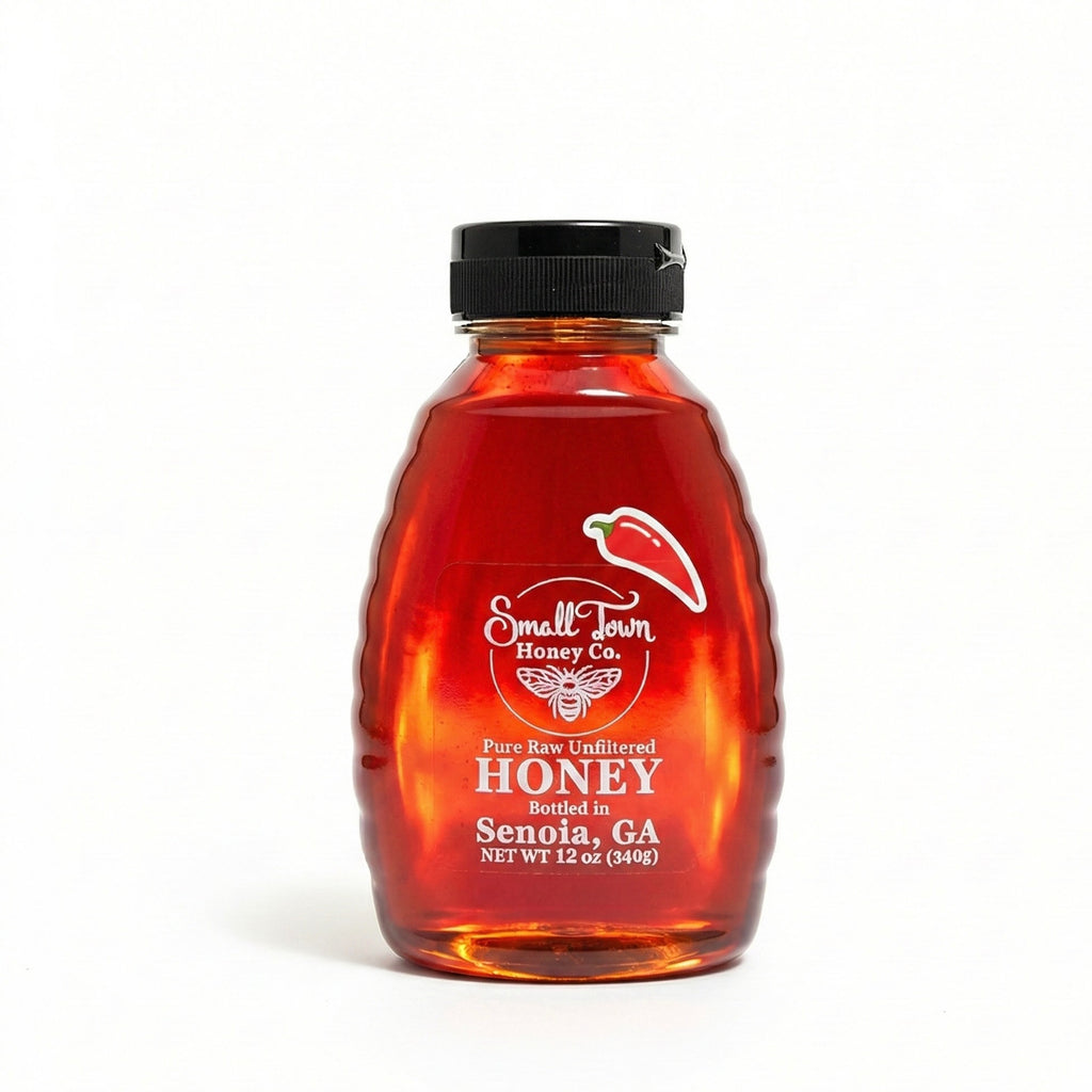 12oz squeeze bottle of Small Town Honey Co. spicy hot honey showing vibrant ruby red color and chili pepper label.