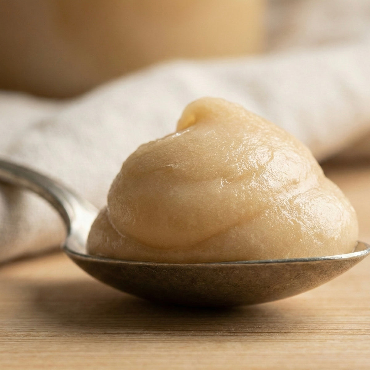 Side view of silver spoon holding a high mound of thick whipped spun honey proving non-drip consistency.